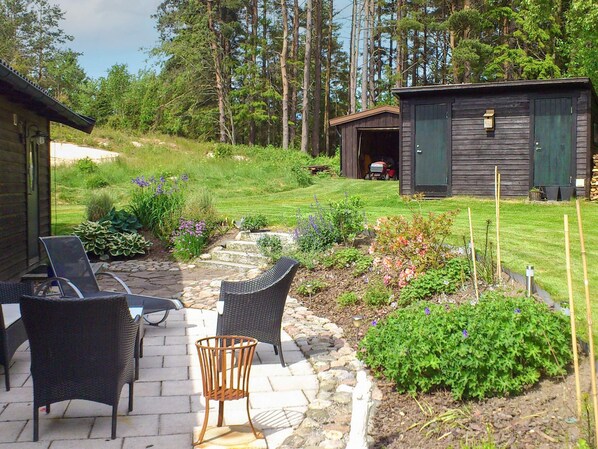A patio with wicker furniture, a stone pathway, and a small garden with various plants. - 6 Person Holiday Home in Hunnebostrand (Kungshamn)