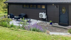 A dark wooden house with a tiled roof, a black door, and a patio with outdoor furniture. - 6 Person Holiday Home in Hunnebostrand (Kungshamn)