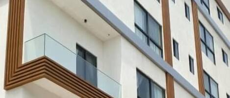 Um hotel com vários andares e design moderno, com varandas, janelas amplas e um telhado plano.