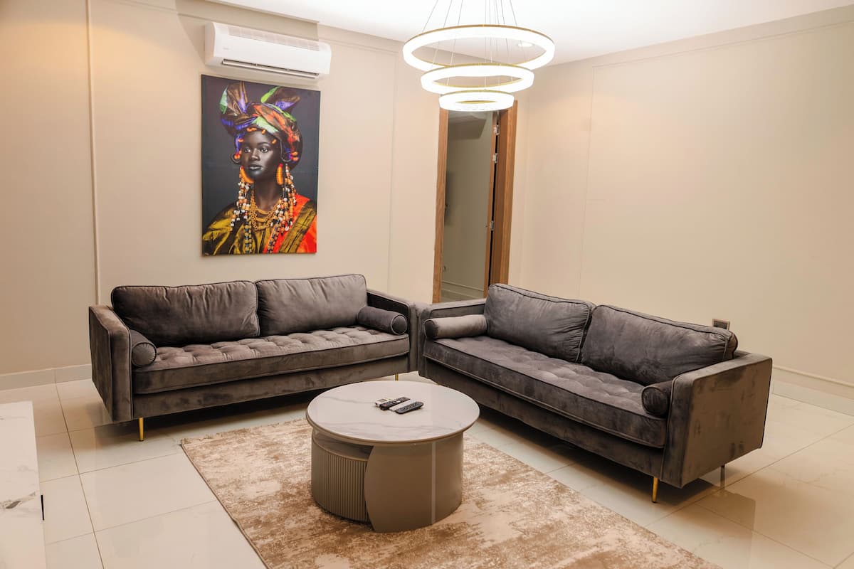 Ein modernes Wohnzimmer mit zwei grauen Sofas, einem runden Couchtisch und einem großen Bild an der Wand.