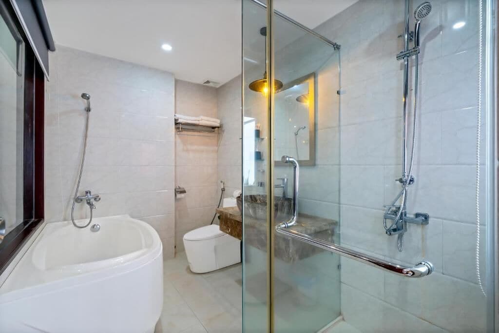 A modern bathroom with a glass-enclosed shower, a standalone bathtub, and a toilet.