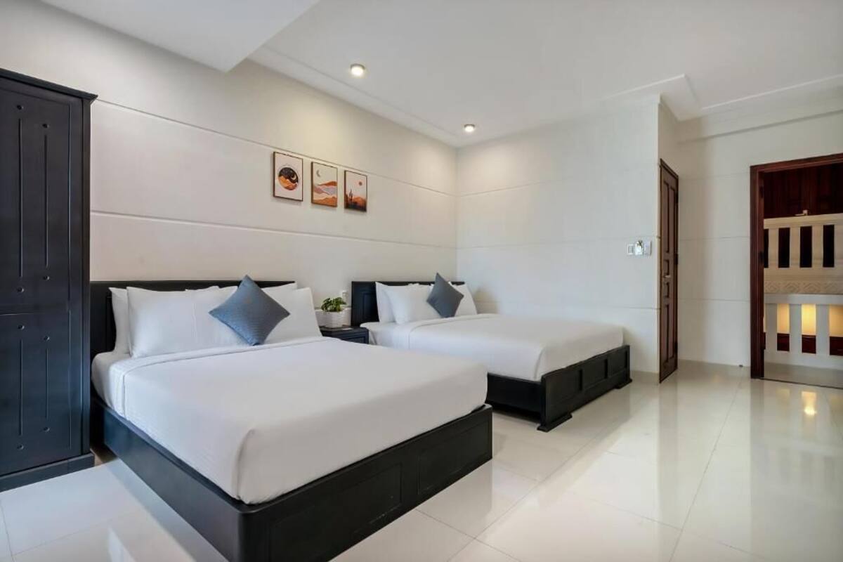 Une chambre d’hôtel avec deux lits, une armoire sombre et une œuvre d’art accrochée au mur.