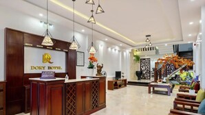 A reception area with a wooden reception desk, a sign reading "DORY HOTEL," and a staircase leading to upper floors. - Dory Hotel (Hoi An)