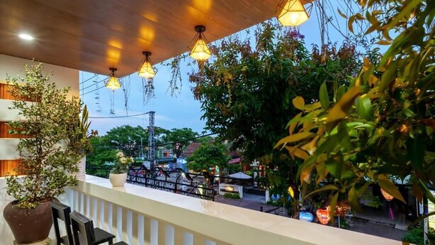 An outdoor seating area with a wooden ceiling, hanging lights, and potted plants. - Dory Hotel (Hoi An)