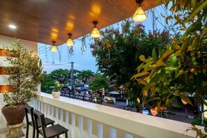 An outdoor seating area with a wooden ceiling, hanging lights, and potted plants. - Dory Hotel (Hoi An)