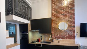 A modern kitchen with a brick accent wall, a built-in oven, and a dining area with a glass table and chairs.