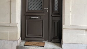 Eine dunkelbraune Tür mit einem rauen Glasfenster und einer kleinen Stufe davor.
