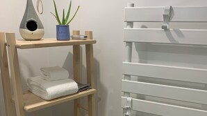 Ein Badezimmer mit einem Holzboden, der Handtücher, eine Topfpflanze und ein dekoratives Objekt beherbergt.