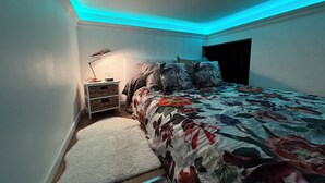A bedroom with a bed, a nightstand, a lamp, and a fluffy rug.