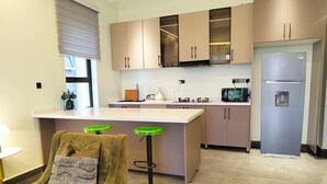 A modern kitchen with a large island, built-in appliances, and a bar stool. - Heritage Residences-Urban Ranger 1BR (Kampala)