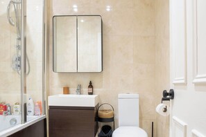 A bathroom with a glass-enclosed shower, a white sink, a toilet, and a towel rack. - Refined 2BDR Family Retreat with Garden in Clapham (Greater London)