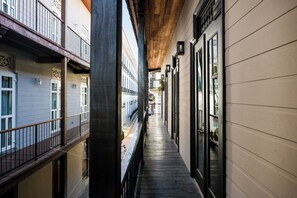 A narrow corridor with wooden flooring, a balcony on the left, and a row of windows on the right. - A fully renovated one-bedroom apartment in the heart of Casco Antiguo, offering private access, refined comfort and an intimate luxury stay for up to 3 guests. (Casco Viejo)