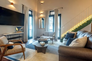 Una sala de estar moderna con un sofá, sillones, una mesa de centro y un televisor de pantalla plana.
