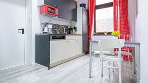 Kompakti keittiö, jossa on mikroaaltouuni, astianpesukone ja pieni ruokailutila, jossa on pöytä ja tuolit.