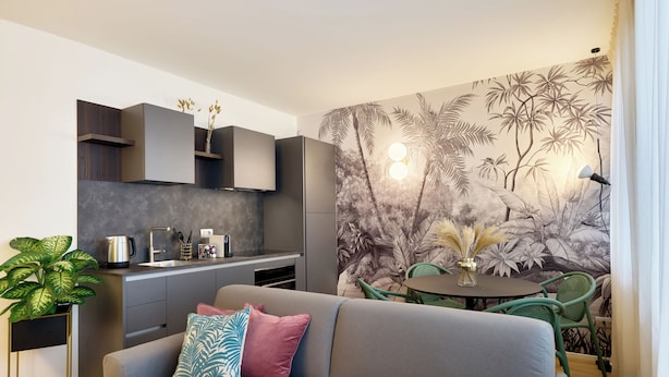Un salon moderne avec un canapé gris, une petite table ronde et un fauteuil vert.