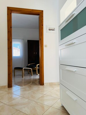 A room with a wooden door leading to another room, a white cabinet with drawers, and a tiled floor. - LP Almyrida - 7 minutes walk from the beach (Almyrida)