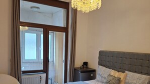 A bedroom with a bed, bedside table, and a chandelier. - Beautiful room (Molenbeek-Saint-Jean)
