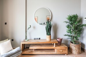 A room with a round mirror, a wooden console table, and two potted plants. - Bloomfields 2BR-Marquis 2020-Arjan (Dubai)
