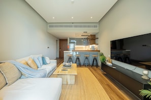 A modern living room with a sofa, coffee table, and a TV mounted on the wall. - Bloomfields 2BR-Marquis 2020-Arjan (Dubai)