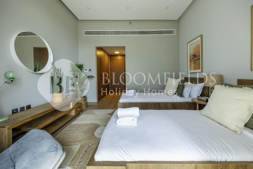Une chambre d’hôtel moderne, dotée d’un grand lit, d’une table de chevet, d’un miroir et donnant sur le couloir.