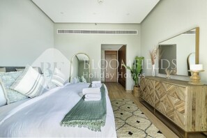 A bedroom with a bed, bedside table, mirror, and a view of a hallway. - Bloomfields Marquis 2020 2br (Dubai)
