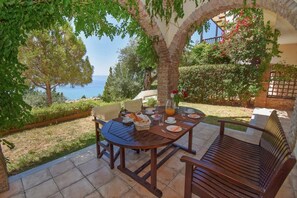 A patio with a table set for breakfast, overlooking a scenic view of the sea. - Daphne Two Bedroom Apartment (Corfu)