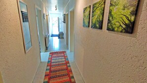 Un corridoio con tappeto decorato, opere d'arte incorniciate alle pareti e soffitto con faretti.