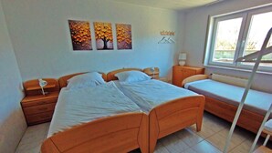 Una camera da letto con due letti, un comodino con una lampada, una finestra vista e un attaccapanni a parete.