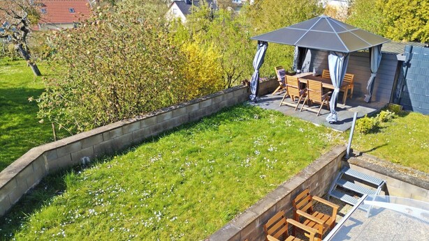 Un immobile residenziale con patio coperto, giardino e vista sui case circostanti.