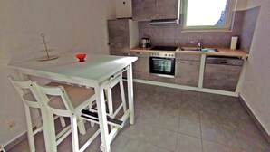 Una cucina funzionale con tavolo e sedie bianche, forno integrato, lavello e una finestra con vista.