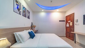 Une chambre d’hôtel bien rangée, avec un lit, une table de chevet, une lampe et des œuvres d’art accrochées au mur.