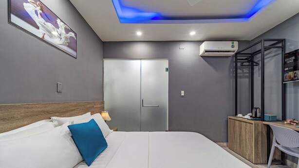 Une chambre d’hôtel moderne équipée d’un lit, d’un bureau, d’une armoire et d’un appareil de climatisation.