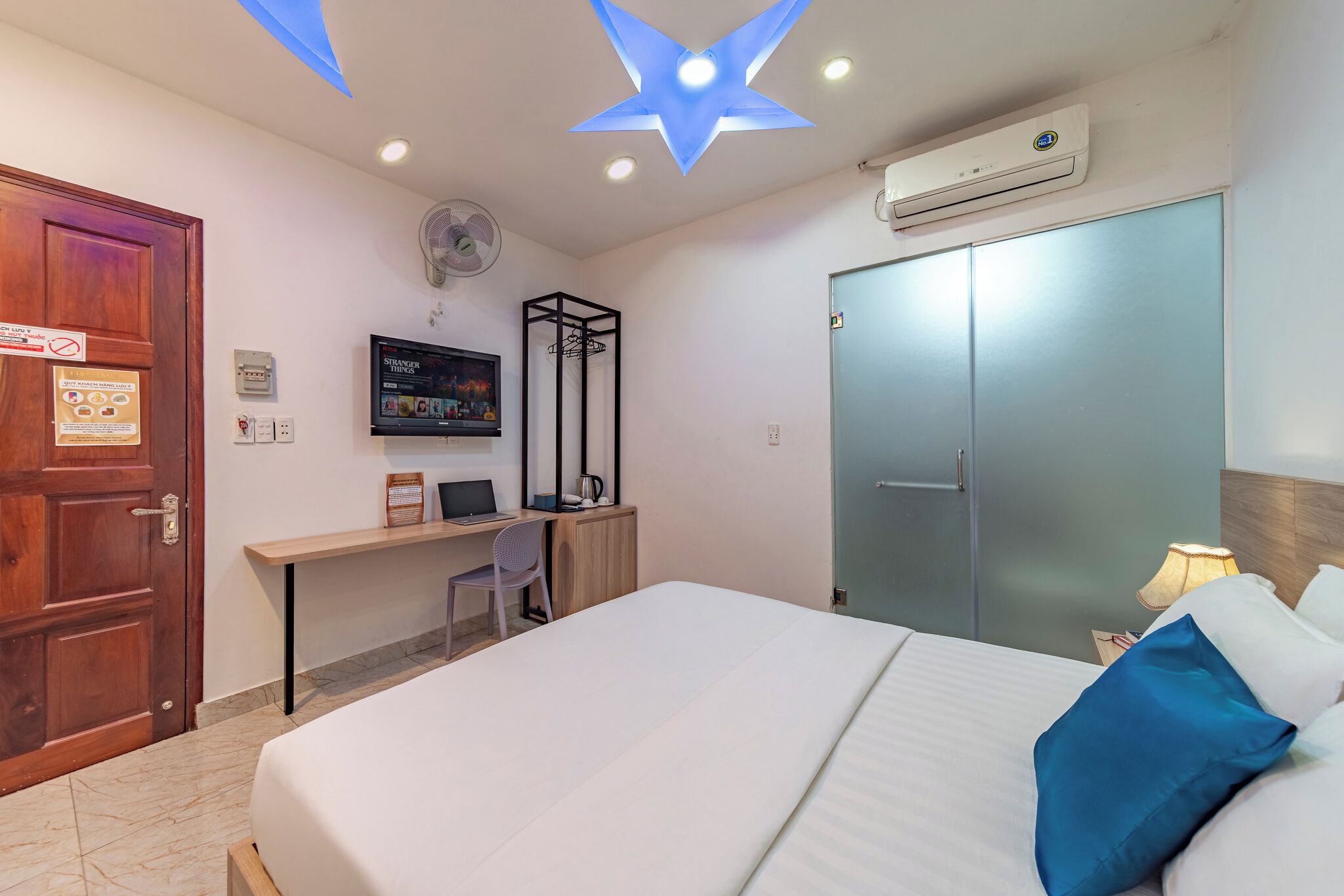 A hotel room with a bed, desk, chair, and wardrobe.