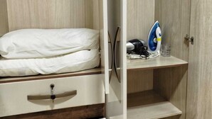 A bedroom with a bed, a dresser, a shelf with an iron and a glass, and a wardrobe. - Ground floor one-bedroom apartment in a condominium with swimming pools and 100 meters from the sea in Florianópolis, SC. (Florianópolis)