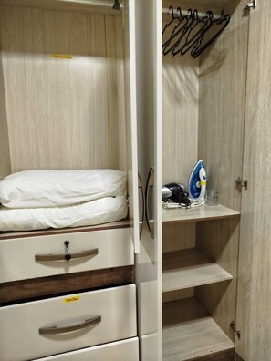 A bedroom with a bed, a dresser, a shelf with an iron and a glass, and a wardrobe. - Ground floor one-bedroom apartment in a condominium with swimming pools and 100 meters from the sea in Florianópolis, SC. (Florianópolis)