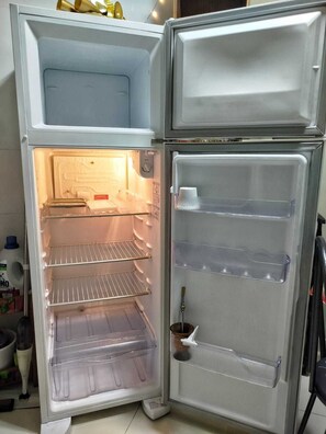 An open refrigerator with multiple shelves and a freezer compartment. - Ground floor one-bedroom apartment in a condominium with swimming pools and 100 meters from the sea in Florianópolis, SC. (Florianópolis)