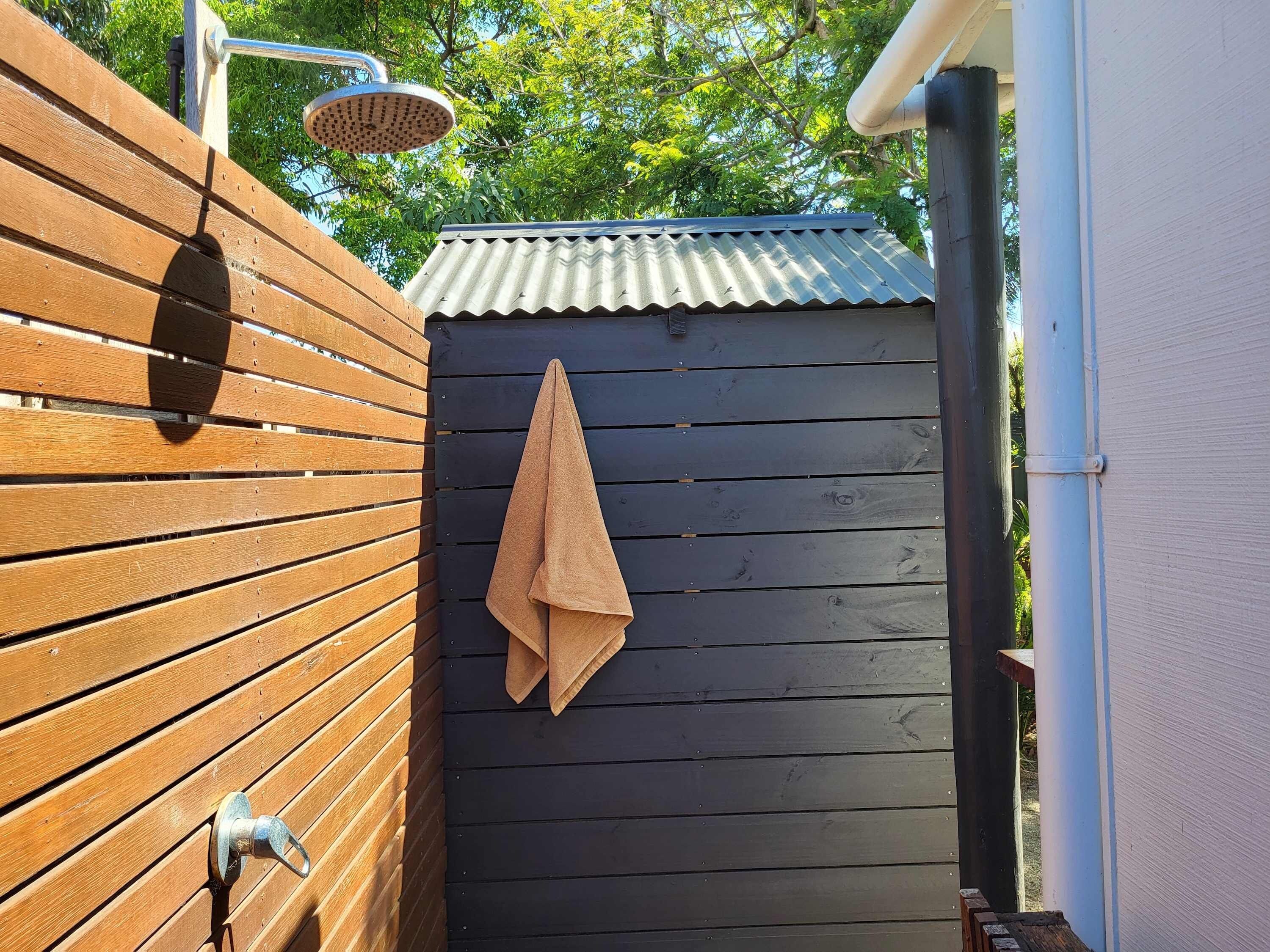 A wooden fence with a towel hanging on it, a metal door, and a corrugated metal roof.