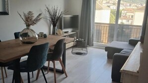 Una sala de estar moderna con comedor, televisor y balcón con vista a un pueblo.