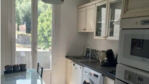 Cocina compacta con lavadora, horno y comedor con mesa y sillas.