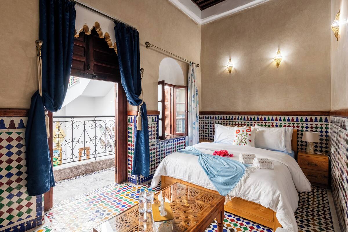 A room with a bed, a small table, and a window with curtains.