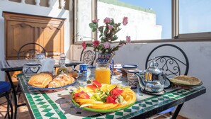 Ein Frühstückstisch mit Croissants, Obst und einem Teekessel.
