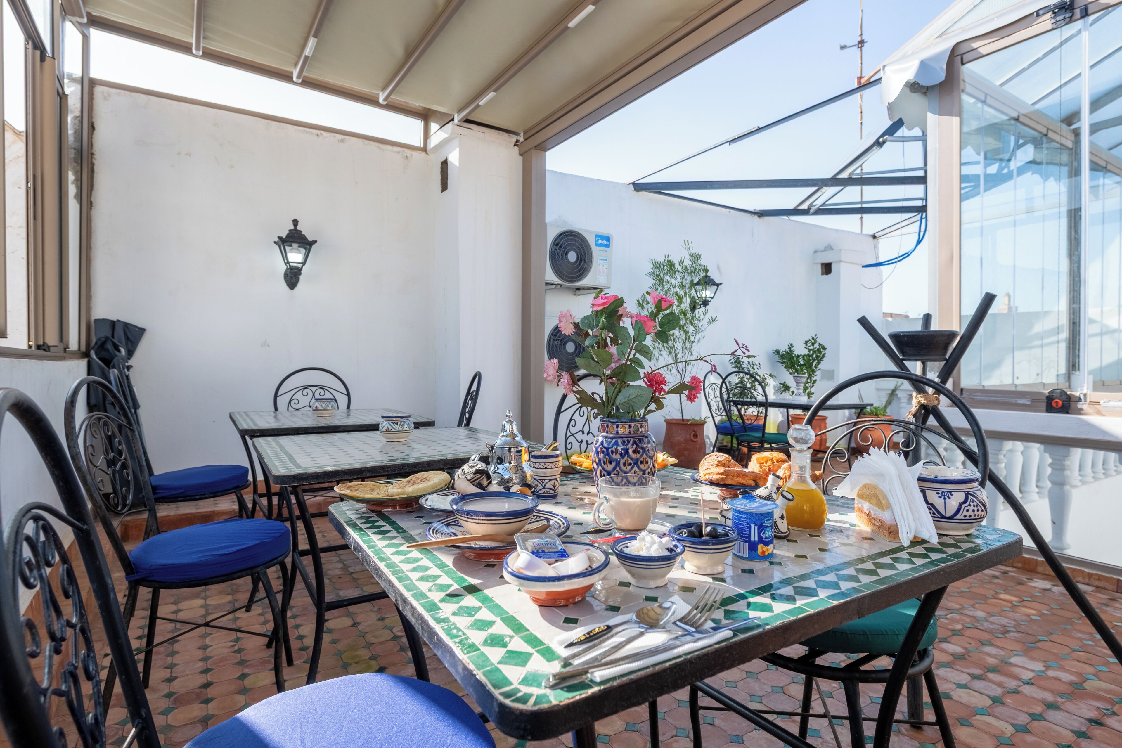 A dining area with a table set for a meal, surrounded by chairs, and a potted plant.