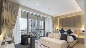 Een moderne hotelkamer met een groot bed, een bank, een bureau met een laptop en uitzicht op de stad door ramen van de vloer tot aan het plafond.