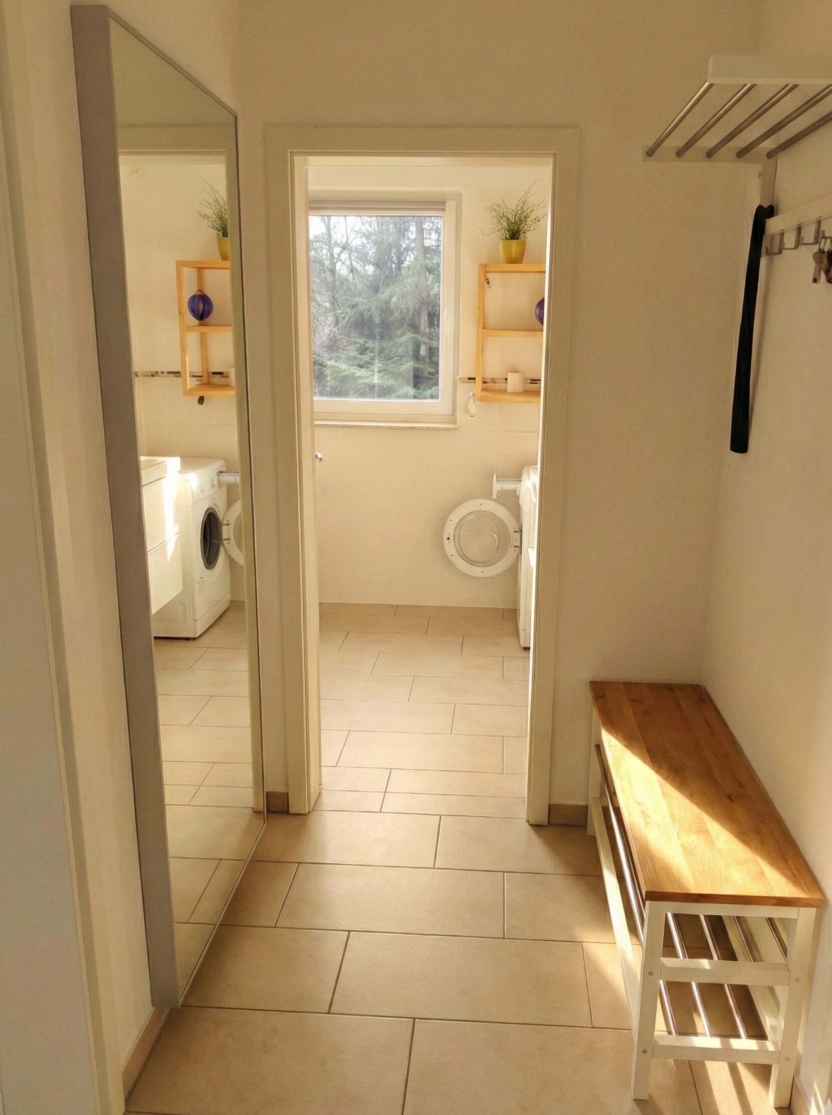 A bathroom with a window, a washing machine, and a toilet.
