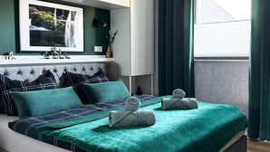 A modern bedroom with a large bed, a mounted TV, and a window with curtains.