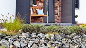 A modern building with a brick facade, a dark-colored entrance, and a bench with cushions outside.