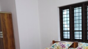 Une chambre à coucher avec une couvre-lit à motifs floraux, une armoire en bois et une fenêtre avec des stores.