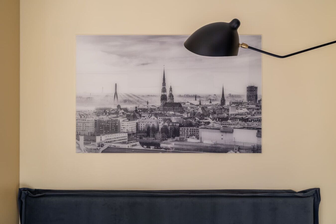 A black and white cityscape photograph on a wall, with a black desk lamp to the right.