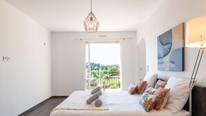 A bedroom with a bed, a view of greenery outside, and a hanging light fixture. - Villa With Swimming Pool, Sauna, Fitness, sea View (Biot)