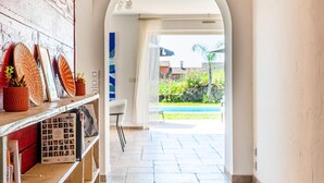 A hallway with a wooden bookshelf, a white chair, and a view of an outdoor area with a pool. - Villa With Swimming Pool, Sauna, Fitness, sea View (Biot)